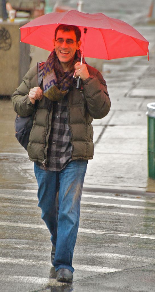 People with umbrellas crossing a rainy city street