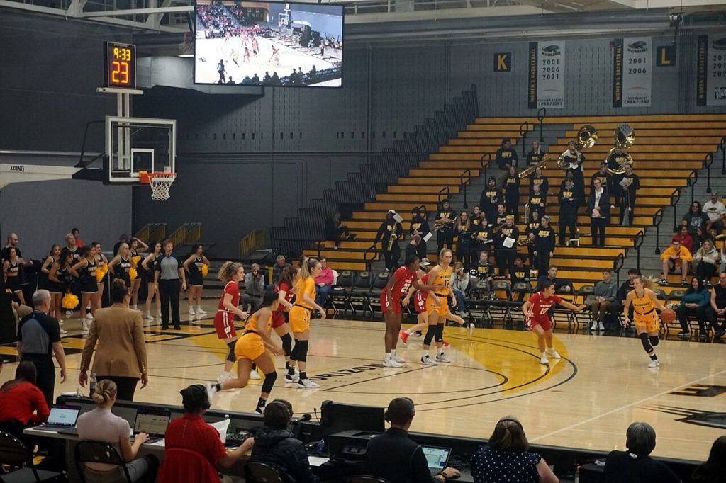 Basketball players competing under arena lights