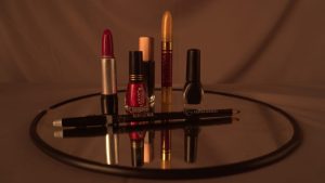 Lipsticks and makeup products arranged on a mirror under warm lighting
